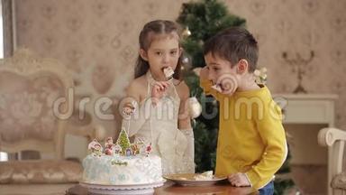 小<strong>女孩和</strong>男孩在<strong>圣诞树</strong>的背景上吃蛋糕。 带<strong>圣诞树</strong>的大客厅